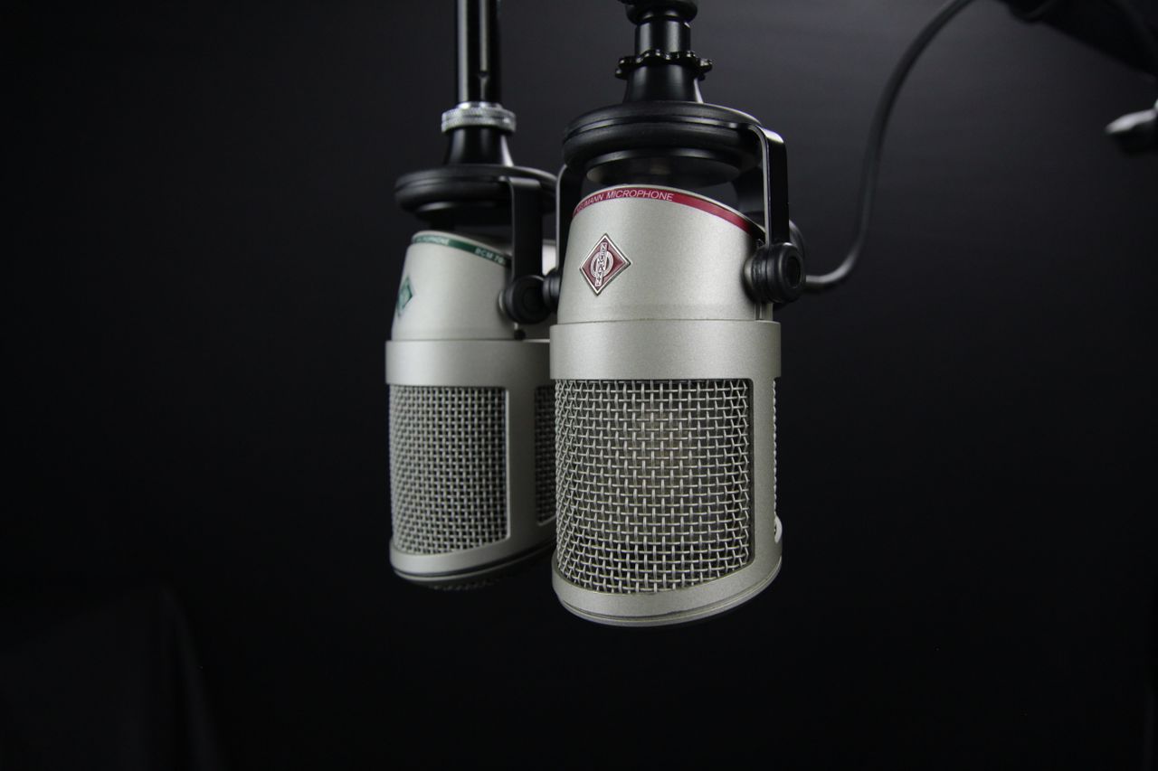 who-we-are Close-up of two professional microphones in a recording studio, ideal for podcasts and music production.